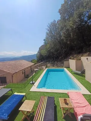 a swimming pool in a yard with two tables and chairs at Haut de Villa Superbe vue Piscine privee in Moltifao
