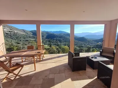a living room with a table and a view of mountains at Haut de Villa Superbe vue Piscine privee in Moltifao