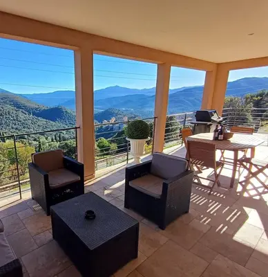 a living room with a table and chairs and mountains at Haut de Villa Superbe vue Piscine privee in Moltifao