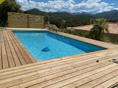 a swimming pool on top of a house with a wooden deck at Cozy villa with pool in Eccica-Suarella