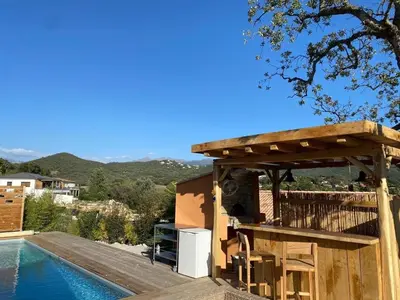 a house with a wooden deck next to a swimming pool at Cozy villa with pool in Eccica-Suarella
