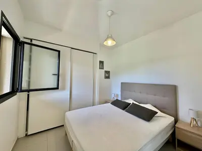 a bedroom with a white bed and a window at T2 à 200m des plages in Propriano