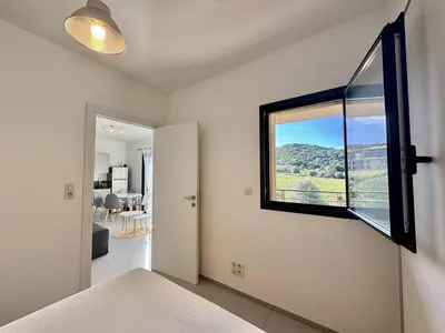 a bedroom with a window and a view of a room at T2 à 200m des plages in Propriano
