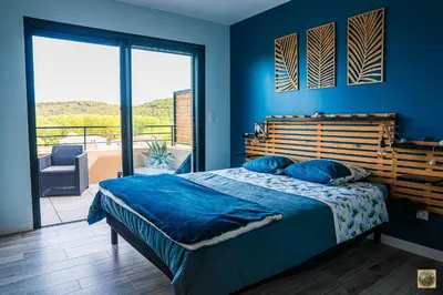 a bedroom with a bed with blue walls and a balcony at Corsu di Core - Villa Core di Favona in Conca
