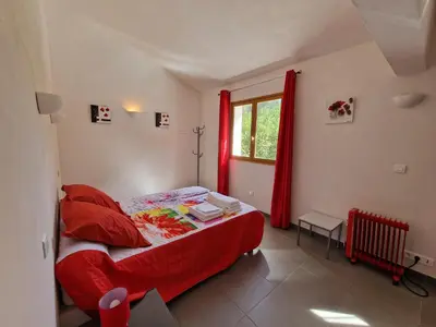 a bedroom with a red bed and a window at Villa pour4 pers à 700m de la plage de palombaggia in Porto-Vecchio