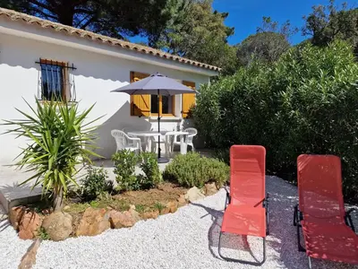 a patio with a table and chairs and an umbrella at Villa pour4 pers à 700m de la plage de palombaggia in Porto-Vecchio