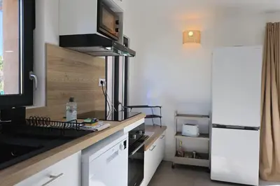 a kitchen with white cabinets and a white refrigerator at A Marinca - Plage privée et piscine chauffée in Pianottoli-Caldarello