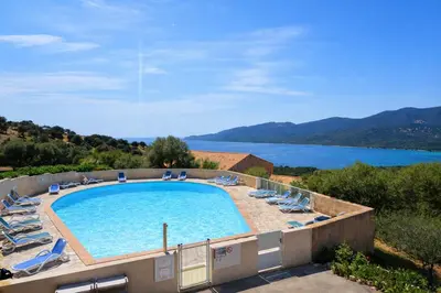a swimming pool with chairs and a view of a lake at Appartement 40 m2 Piscine vue panoramique sur Cupabia in Serra-di-Ferro