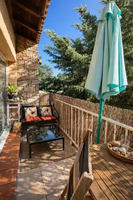 a patio with an umbrella and a bench and a table at Appartement 40 m2 Piscine vue panoramique sur Cupabia in Serra-di-Ferro