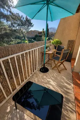 a patio with an umbrella and a table and chairs at Appartement 40 m2 Piscine vue panoramique sur Cupabia in Serra-di-Ferro