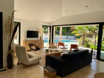 a living room with a black couch and a large window at Villa Mare e Monte - Cala Rossa in Porto-Vecchio
