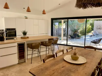 a kitchen and dining room with a wooden table and chairs at Villa Mare e Monte - Cala Rossa in Porto-Vecchio