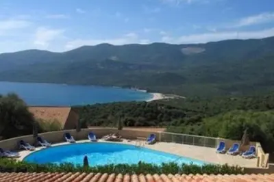 a swimming pool with chairs and a view of a lake at Mini villa dans résidence calme wifi piscine mer à pied in Serra-di-Ferro