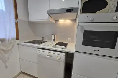 a white kitchen with a sink and a stove at Mini villa dans résidence calme wifi piscine mer à pied in Serra-di-Ferro