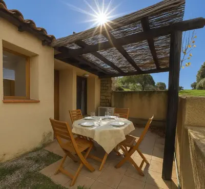 a patio with a table and chairs under a pergola at Mini villa dans résidence calme wifi piscine mer à pied in Serra-di-Ferro