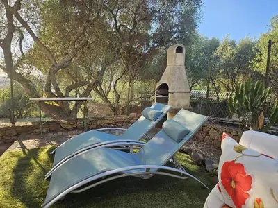 a blue chair sitting on the grass in a yard at La Maisonnette , 2 personnes, charming cottage, 4 km from the beaches in Cargèse