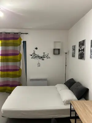 a bedroom with a white bed and a table at Charmant studio en centre-ville in Corte