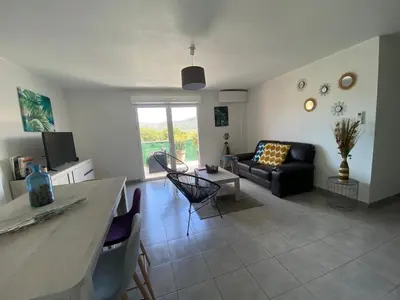 a living room with a couch and a table at Entire air-conditioned accommodation, Porto Vecchio center in Porto-Vecchio