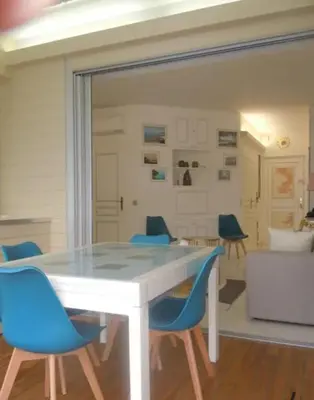 a dining room with a white table and blue chairs at Appartement les pieds dans l'eau in Calcatoggio