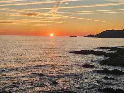 a sunset over a body of water with rocks at Appartement les pieds dans l'eau in Calcatoggio