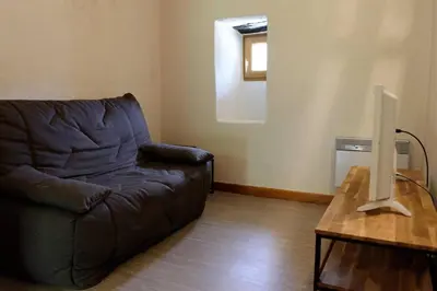 a living room with a couch and a television on a table at Agréable triplex Nelly situé en moyenne montagne in Cristinacce