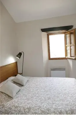 a white bedroom with a bed and a window at Agréable triplex Nelly situé en moyenne montagne in Cristinacce