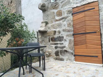 a table and chairs in front of a stone wall at Agréable triplex Nelly situé en moyenne montagne in Cristinacce