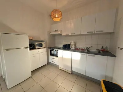 a kitchen with white cabinets and a white refrigerator at T3 - accès direct plage dans résidence avec piscine in Poggio-Mezzana