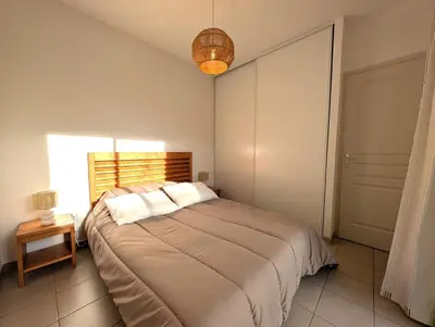 a bedroom with a large bed and a lamp at T3 - accès direct plage dans résidence avec piscine in Poggio-Mezzana