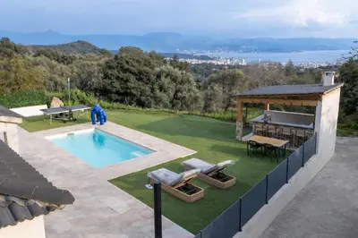 a living room with a couch and a kitchen at Villa moderne piscine vue mer in Ajaccio