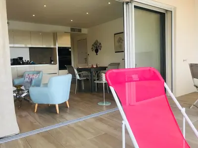 a living room with a pink couch and a kitchen at Appartement vue mer Piscine Solenzara Résidence Mare Festa B132 in Kamiesch