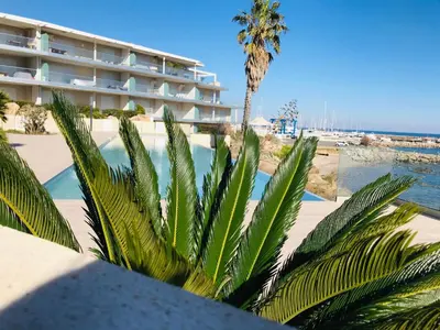 a hotel with a palm tree and a swimming pool at Appartement vue mer Piscine Solenzara Résidence Mare Festa B132 in Kamiesch