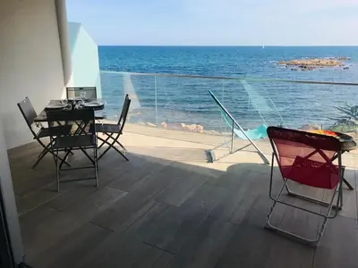 a table and chairs on a balcony with the ocean at Appartement vue mer Piscine Solenzara Résidence Mare Festa B132 in Kamiesch