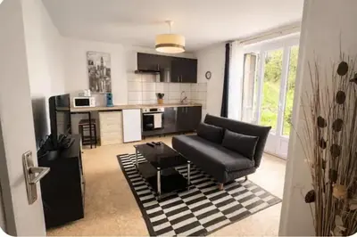 a living room with a black couch and a kitchen at Chez MANI in Eccica-Suarella