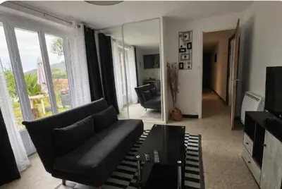 a living room with a black couch and a mirror at Chez MANI in Eccica-Suarella