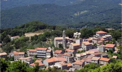 a group of houses on a hill with mountains in the background at Maison de village typique en Corse mer montagne