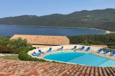 a swimming pool with chairs and a body of water at Appartement rénové pour 6 pers tout équipé dans résidence piscine & mer in Serra-di-Ferro