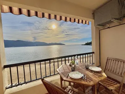 a balcony with a table and a view of the ocean at Studio terrasse vue mer Tiuccia in Calcatoggio
