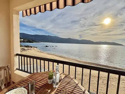 a balcony with a table and a view of the beach at Studio terrasse vue mer Tiuccia in Calcatoggio