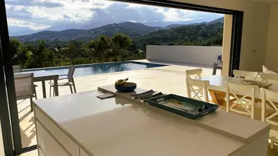 a kitchen and dining room with a view of the mountains at Villa Casalonga, 8 pers, piscine chauffée, 1km plage in Cirendinu