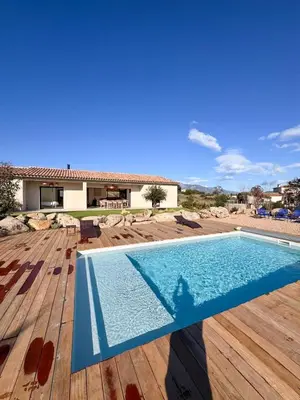 a swimming pool on a wooden deck with a house at Casa Cagna, 3 bedrooms, Heated pool, 8people in Figari