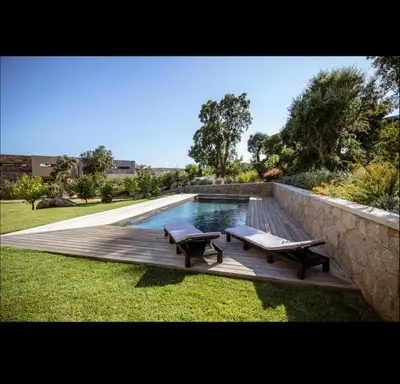 a swimming pool with two benches on a wooden deck at Villa L'Orangerie, 4 Bedrooms, 8 People, pool, Lecci in Lecci