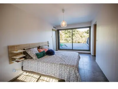 a bedroom with a bed and a large window at Villa l'orangerie, 2 chambres , Piscine, 4personnes in Lecci