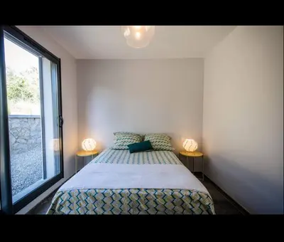 a bedroom with a bed and two lamps on two tables at Villa l'orangerie, 2 chambres , Piscine, 4personnes in Lecci