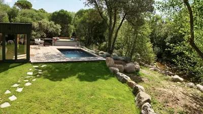 a swimming pool in a yard with rocks around it at Chalet Alivi in Porto-Vecchio