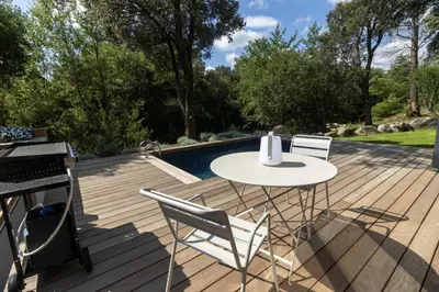 a deck with a table and chairs next to a pool at Chalet Alivi in Porto-Vecchio