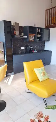 a yellow chair in a room with a kitchen at Appartement 