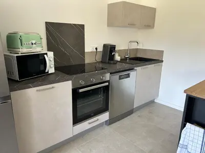 a kitchen with a stove and a microwave at Villa Corail- Piscine privée- Corsu di Core in Conca