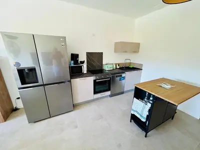a kitchen with a refrigerator and a table in it at Villa Corail- Piscine privée- Corsu di Core in Conca