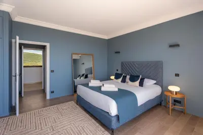 a bedroom with a large bed with blue walls at Château di Cardiccia a Luxury 7-Bedroom Villa with Air Conditioning in Zonza